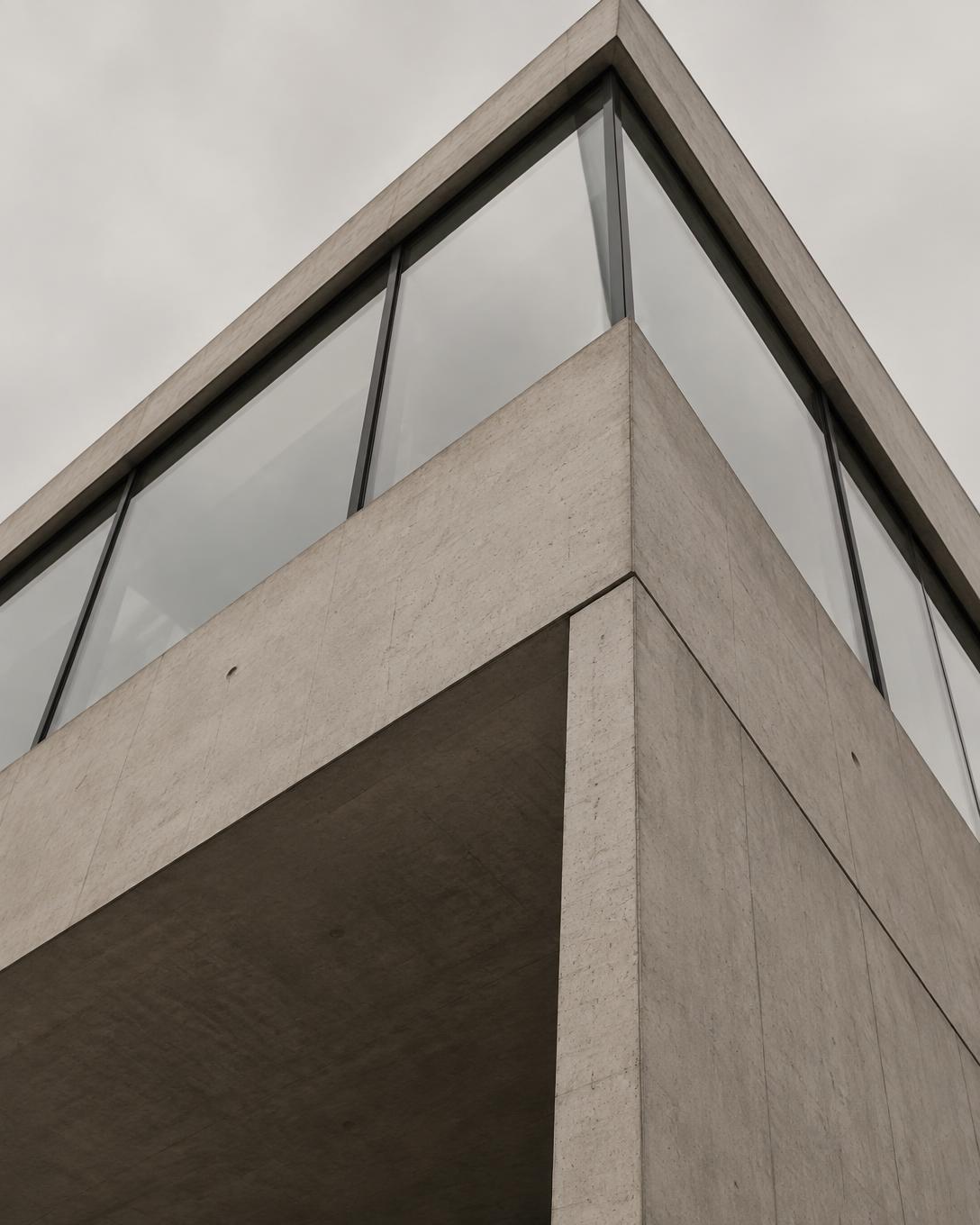 Hoek van een betonnen gebouw met glazen gevel, van onderaf gezien